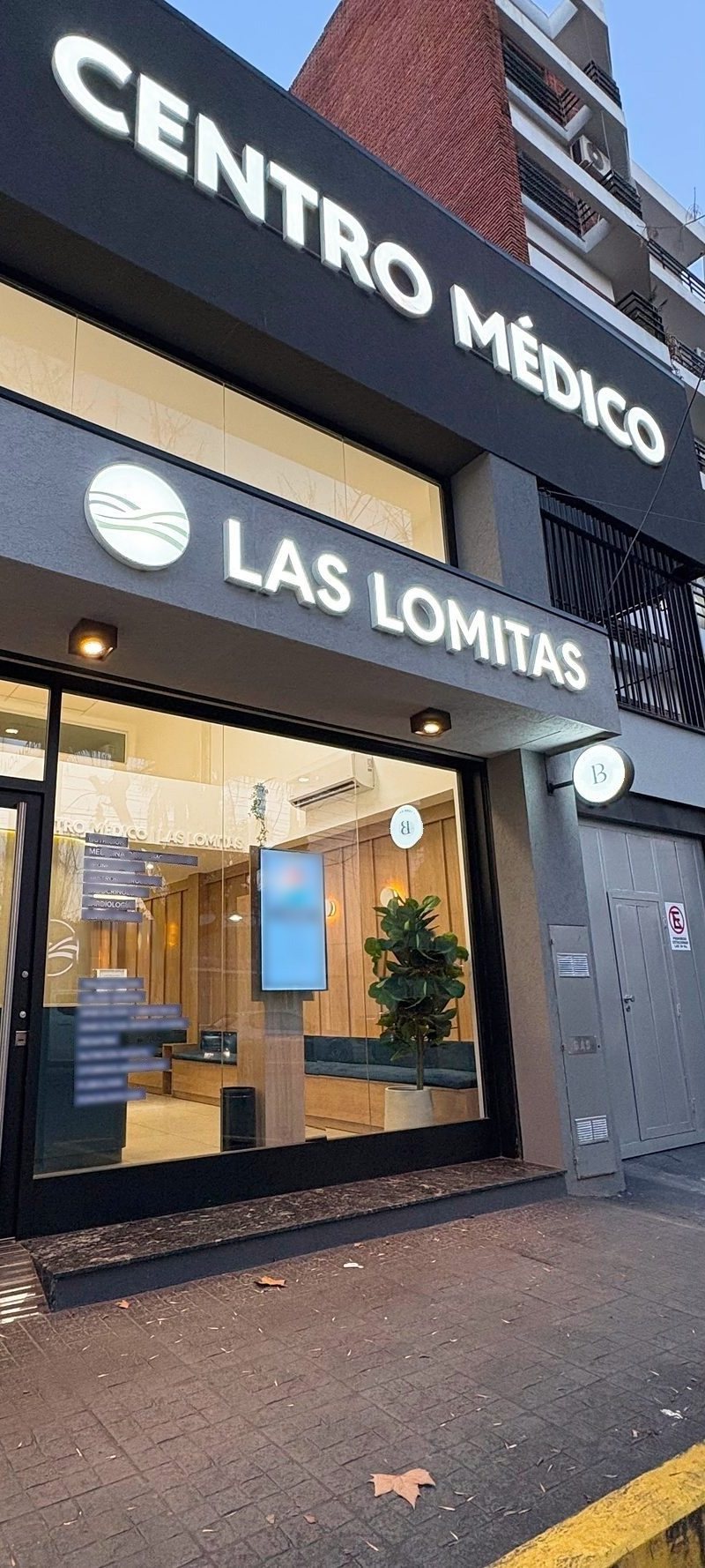 Fachada del Centro Médico Las Lomitas al atardecer, con el cartel encendido